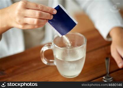 healthcare, medicine and people concept - close up of woman pouring medication into cup of water
