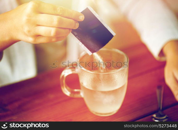 healthcare, medicine and people concept - close up of woman pouring medication into cup of water. woman pouring medication into cup of water