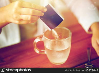 healthcare, medicine and people concept - close up of woman pouring medication into cup of water. woman pouring medication into cup of water