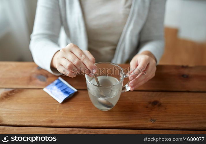 healthcare, medicine and people concept - close up of woman stirring medication in cup with spoon