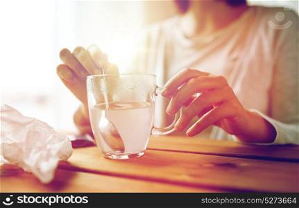 healthcare, medicine and people concept - close up of woman stirring medication in cup with spoon. woman stirring medication in cup with spoon
