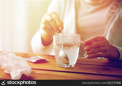 healthcare, medicine and people concept - close up of woman stirring medication in cup with spoon. woman stirring medication in cup with spoon