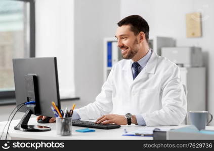 healthcare, medicine and people concept - happy smiling male doctor with computer working at hospital. male doctor with computer working at hospital