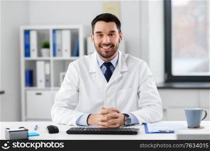 healthcare, medicine and people concept - happy smiling male doctor with earphones having video conference at hospital. doctor in earphones having video call at clinic