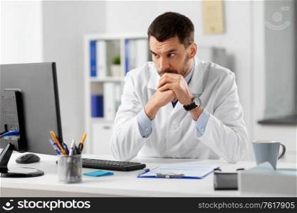 healthcare, medicine and people concept - male doctor with clipboard and computer working at hospital. doctor with clipboard and computer at hospital
