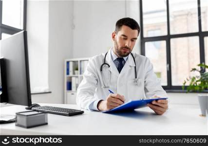 healthcare, medicine and people concept - male doctor with clipboard at hospital. male doctor with clipboard at hospital