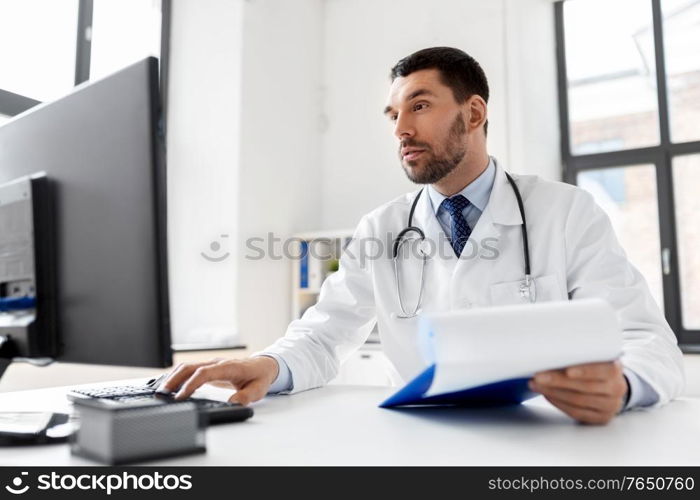 healthcare, medicine and people concept - male doctor with computer working at hospital. male doctor with computer working at hospital