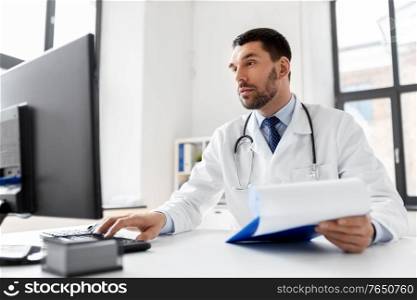 healthcare, medicine and people concept - male doctor with computer working at hospital. male doctor with computer working at hospital