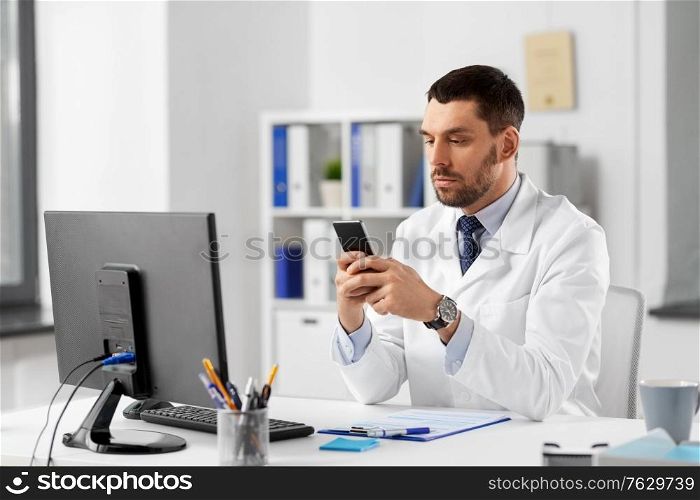 healthcare, medicine and people concept - male doctor with smartphone at hospital. male doctor with smartphone at hospital