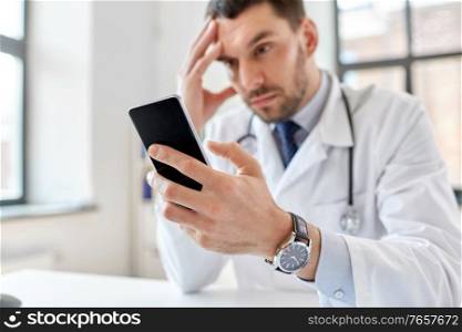 healthcare, medicine and people concept - male doctor with smartphone at hospital. male doctor with smartphone at hospital