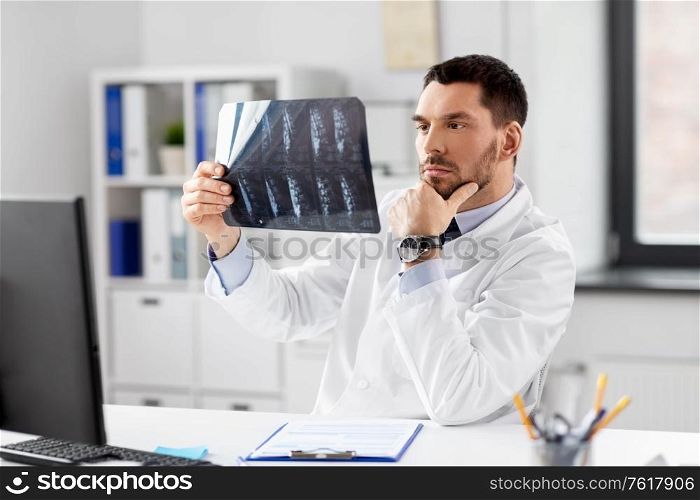 healthcare, medicine and people concept - male doctor with x-ray of spine at hospital. male doctor with x-ray of spine at hospital
