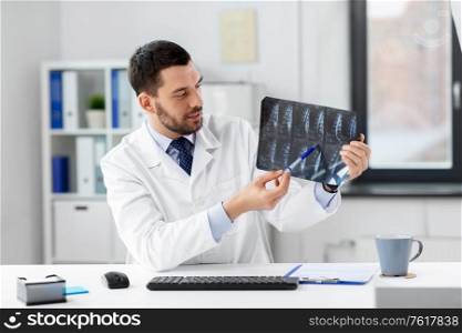 healthcare, medicine and people concept - male doctor with x-ray scan of spine having video conference at hospital. doctor with x-ray having video call at clinic