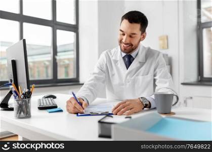 healthcare, medicine and people concept - smiling male doctor with clipboard at hospital. smiling male doctor with clipboard at hospital