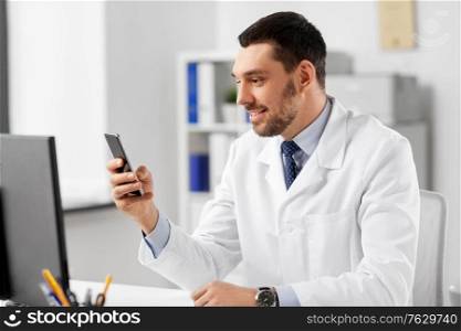 healthcare, medicine and people concept - smiling male doctor with smartphone at hospital. smiling male doctor with smartphone at hospital