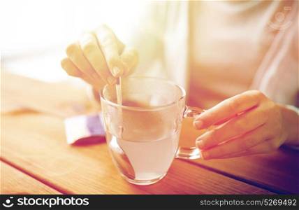 healthcare, medicine and people concept - woman stirring medication in cup of water with spoon. woman stirring medication in cup of water