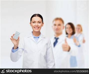healthcare, medicine and pharmacy concept - smiling female doctor and with pills