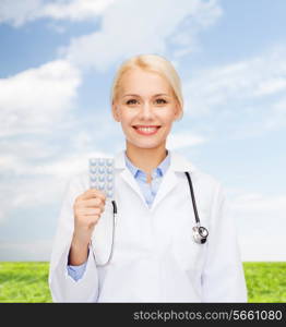 healthcare, medicine and pharmacy concept - smiling female doctor and with pills and stethoscope