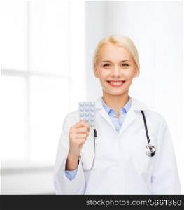 healthcare, medicine and pharmacy concept - smiling female doctor and with pills and stethoscope