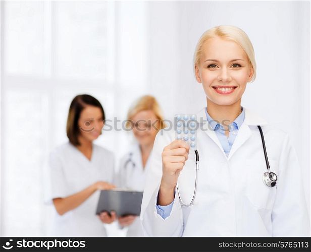 healthcare, medicine and pharmacy concept - smiling female doctor and with pills and stethoscope