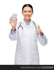 healthcare, medicine and pharmacy concept - smiling female doctor with stethoscope and pills