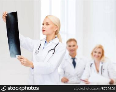 healthcare, medicine and radiology concept - serious female doctor looking at x-ray