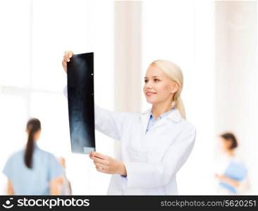 healthcare, medicine and radiology concept - smiling female doctor looking at x-ray over hospital background with group of medics