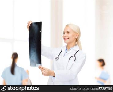 healthcare, medicine and radiology concept - smiling female doctor looking at x-ray image over clinic background