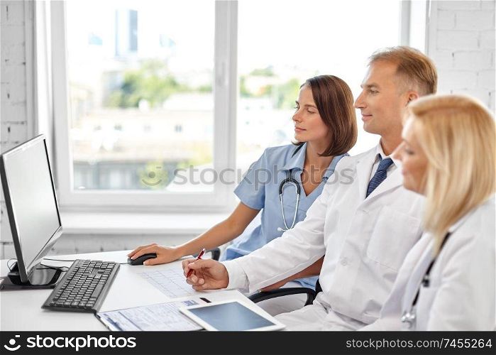 healthcare, medicine and technology concept - group of doctors with computer at hospital. group of doctors with computer at hospital