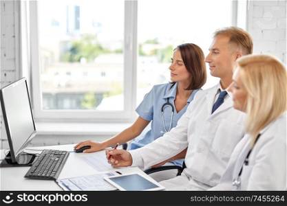 healthcare, medicine and technology concept - group of doctors with computer at hospital. group of doctors with computer at hospital