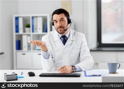 healthcare, medicine and technology concept - happy male doctor with headset having video call at hospital. male doctor in headset having video call at clinic