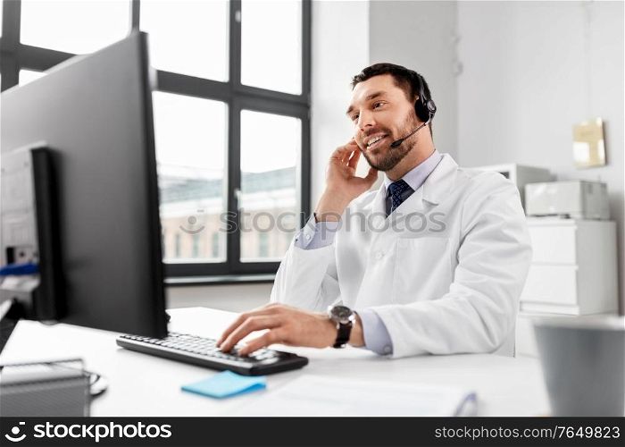 healthcare, medicine and technology concept - happy smiling male doctor with computer and headset working at hospital. happy doctor with computer and headset at hospital