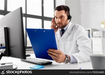 healthcare, medicine and technology concept - male doctor with headset and clipboard working at hospital. male doctor with headset and clipboard at hospital