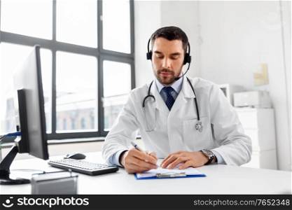 healthcare, medicine and technology concept - male doctor with headset and clipboard working at hospital. male doctor with headset and clipboard at hospital