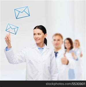 healthcare, medicine and technology concept - smiling female doctor pointing to envelope