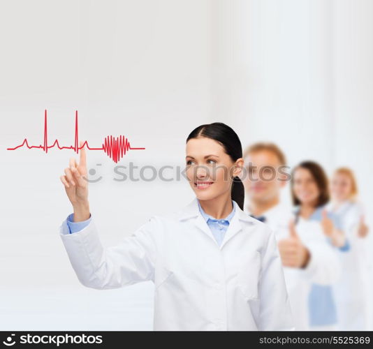 healthcare, medicine and technology concept - smiling female doctor pointing to heart and cardiogram