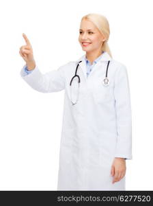 healthcare, medicine and technology concept - smiling female doctor with stethoscope pointing to something or pressing imaginary button