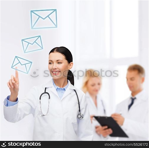 healthcare, medicine and technology concept - smiling female doctor with stethoscope pointing to envelope