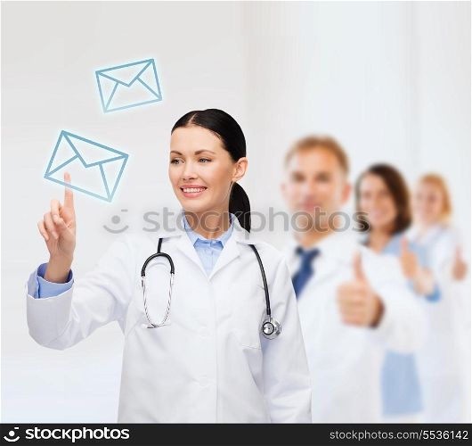 healthcare, medicine and technology concept - smiling female doctor with stethoscope pointing to envelope
