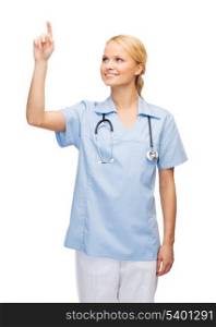 healthcare, medicine and technology concept - smiling young doctor or nurse pointing to something or pressing imaginary button