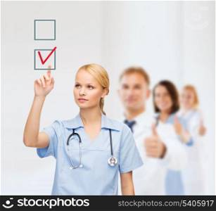 healthcare, medicine and technology concept - smiling young doctor or nurse pointing to red checkmark in checkbox