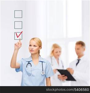 healthcare, medicine and technology concept - smiling young doctor or nurse pointing to red checkmark in checkbox