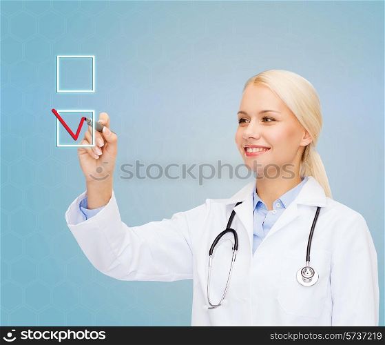 healthcare, medicine and technology concept - smiling young female doctor drawing mark to check box over blue background