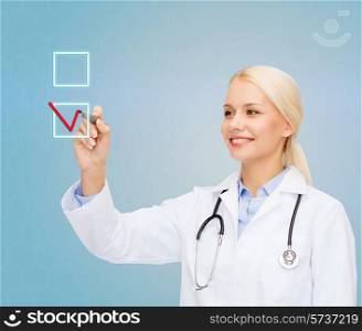 healthcare, medicine and technology concept - smiling young female doctor drawing mark to check box over blue background