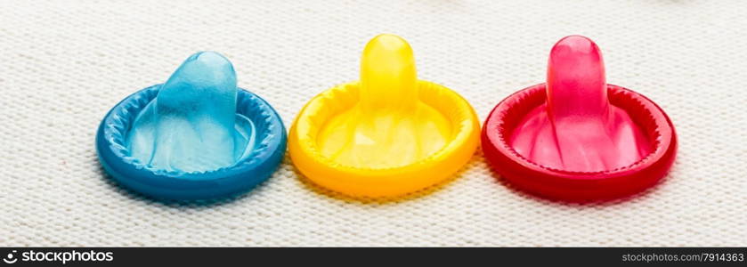 Healthcare medicine, contraception and birth control. Closeup colorful condoms on white cloth.