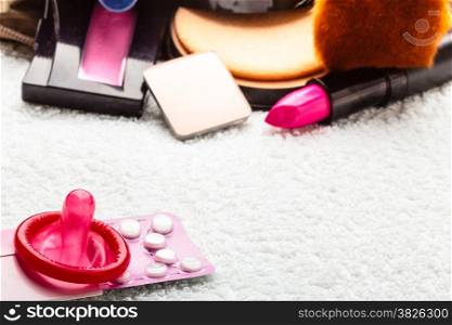 Healthcare medicine, contraception and birth control. Closeup oral contraceptive pills, condom and cosmetics in handbag.
