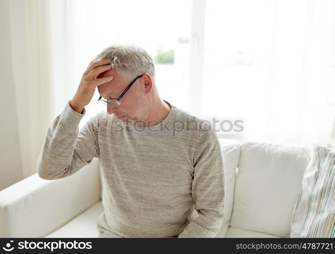 healthcare, pain, stress, age and people concept - senior man suffering from headache at home