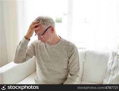healthcare, pain, stress, age and people concept - senior man suffering from headache at home