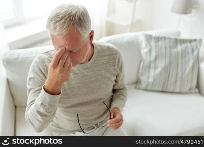 healthcare, pain, stress, age and people concept - senior man suffering from headache at home