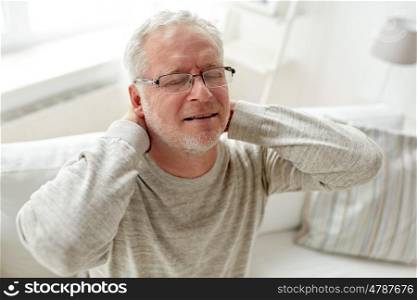 healthcare, pain, stress, age and people concept - senior man suffering from neckache at home
