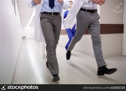 healthcare, people and medicine concept - close up of medics or doctors running along hospital corridor